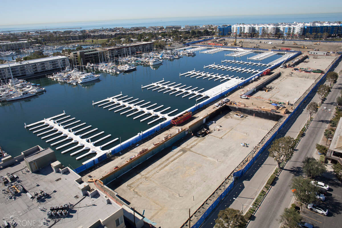 Aerial view of large-scale waterfront construction site with below-grade waterproofing installation