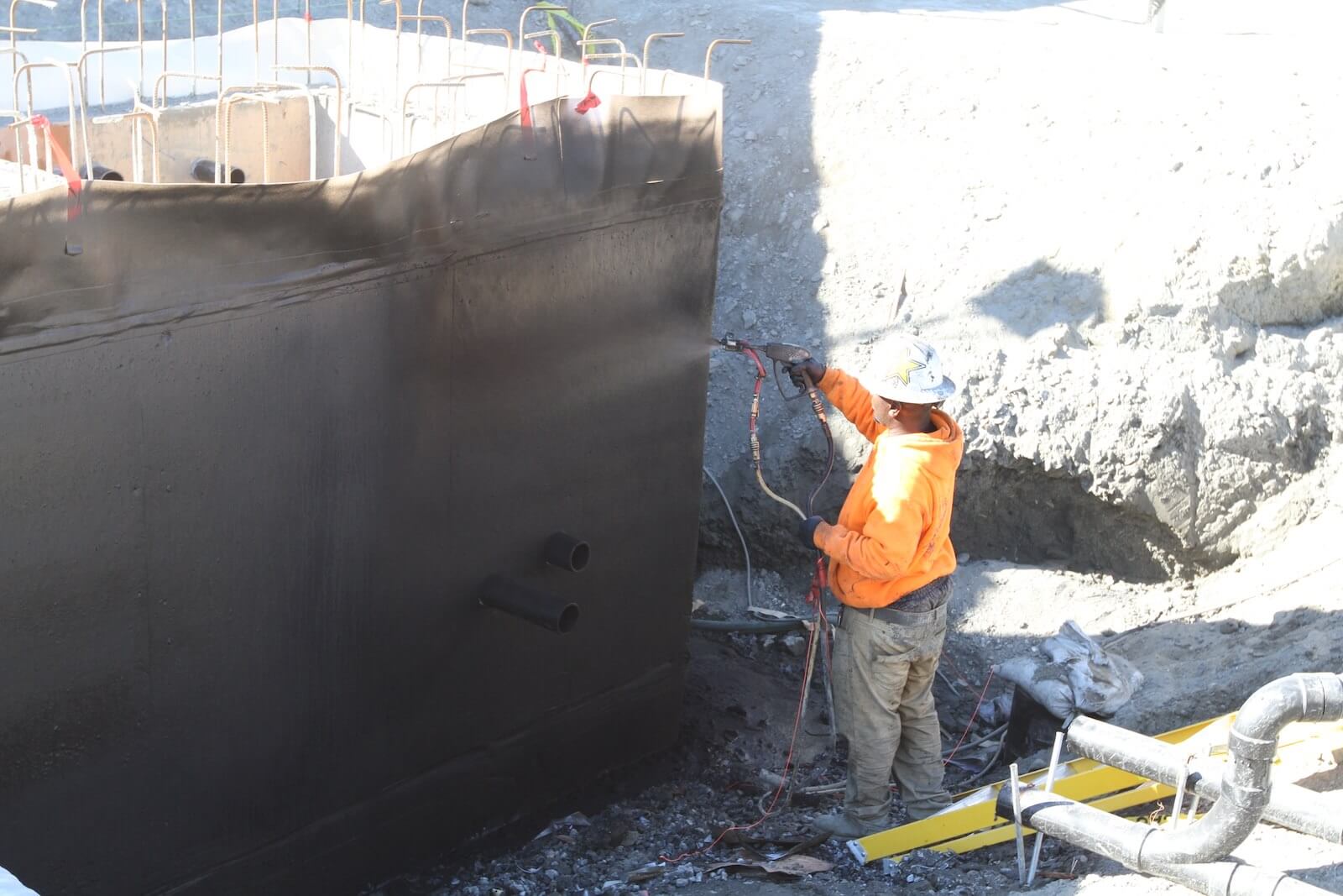 Application of liquid waterproofing coating over concrete foundation wall