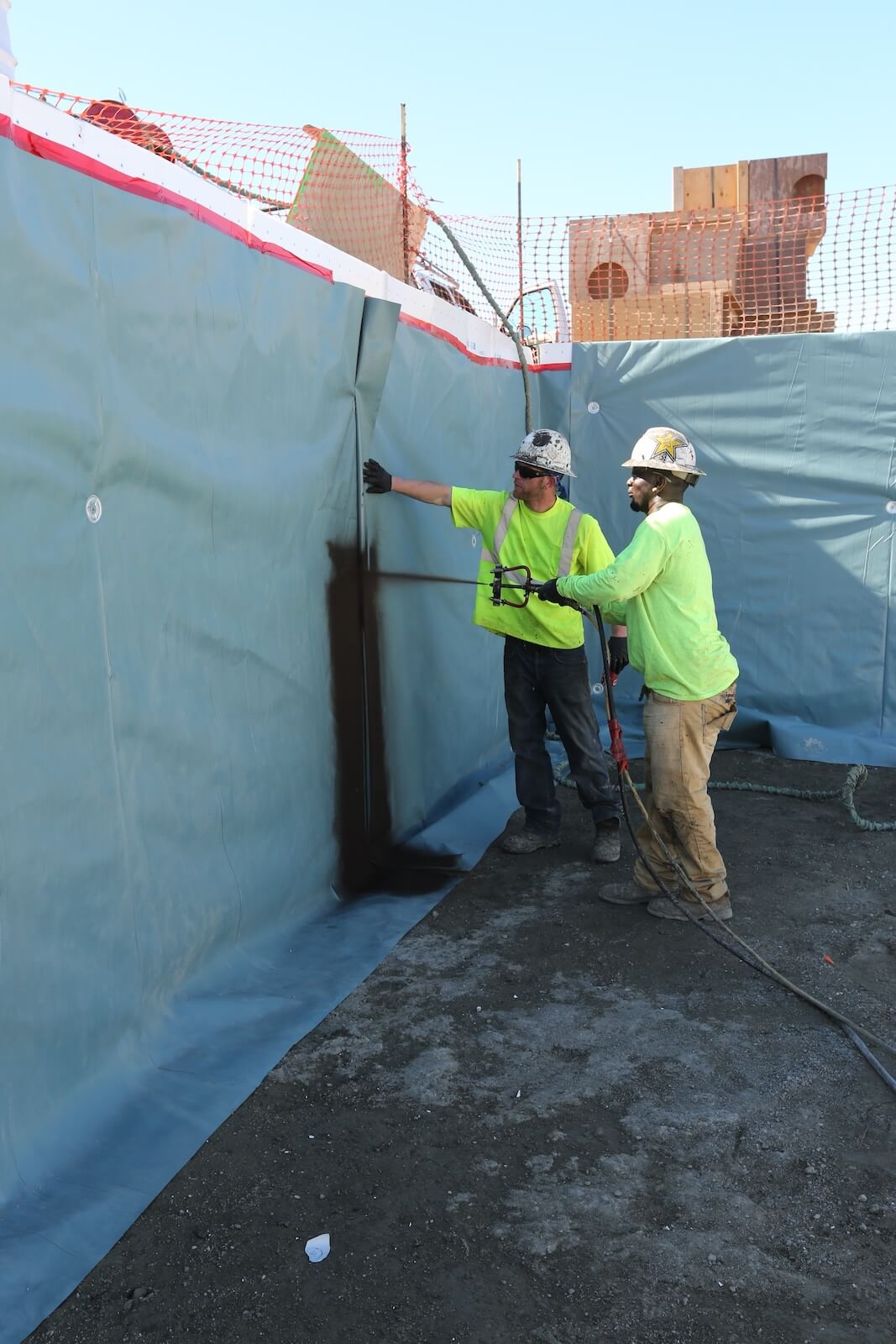 Crew installing Aussie Skin 550G sheet waterproofing membrane on vertical wall surface