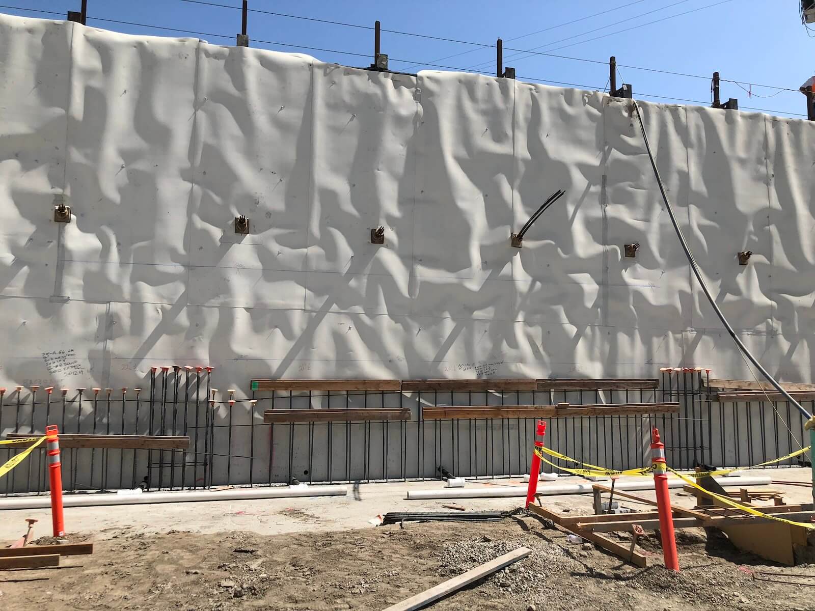 Close-up of blindside waterproofing membrane with tiebacks and wall penetrations